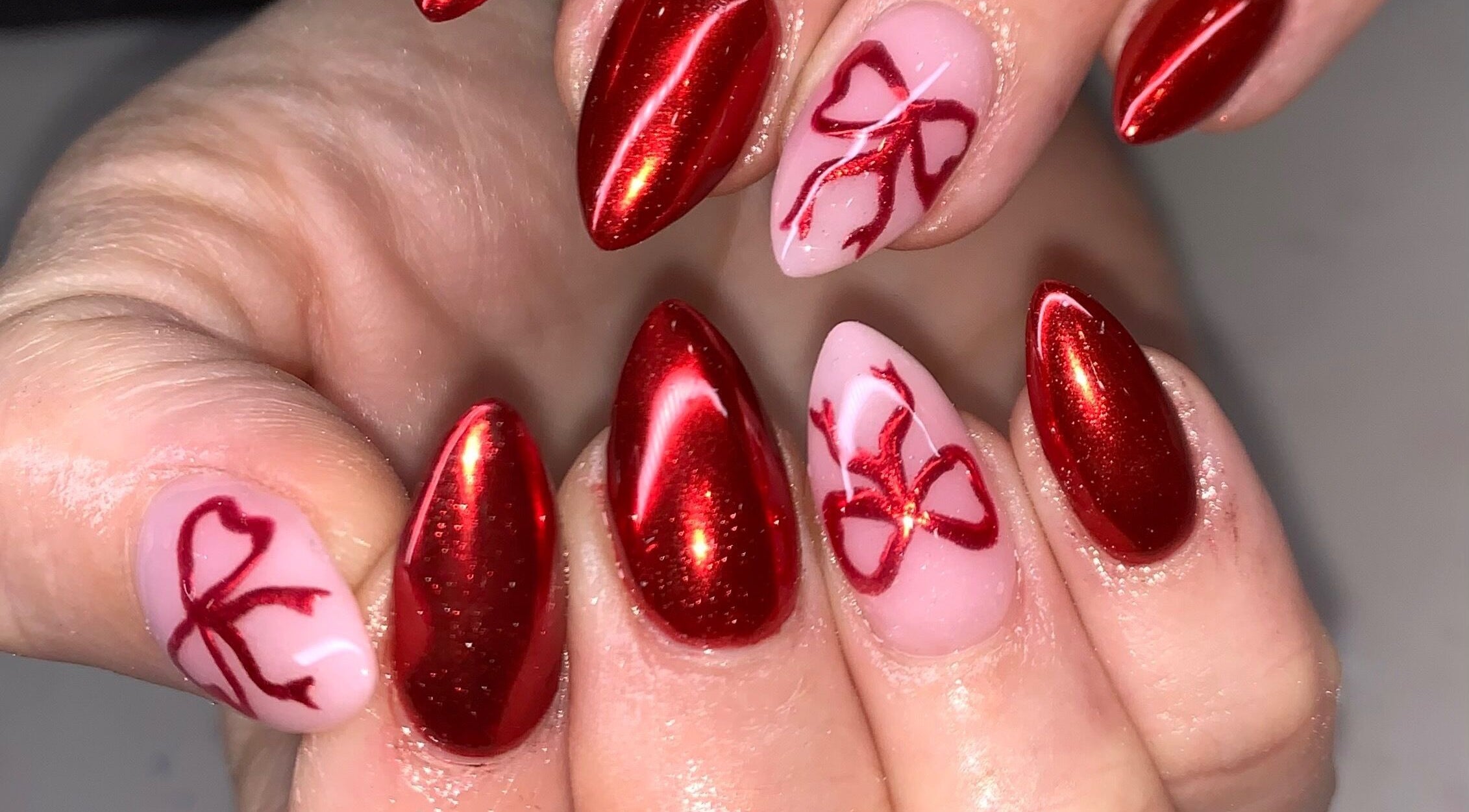 Elegant red nails with bow art at Luxx Nails & Spa, Canonsburg, Pennsylvania, US.