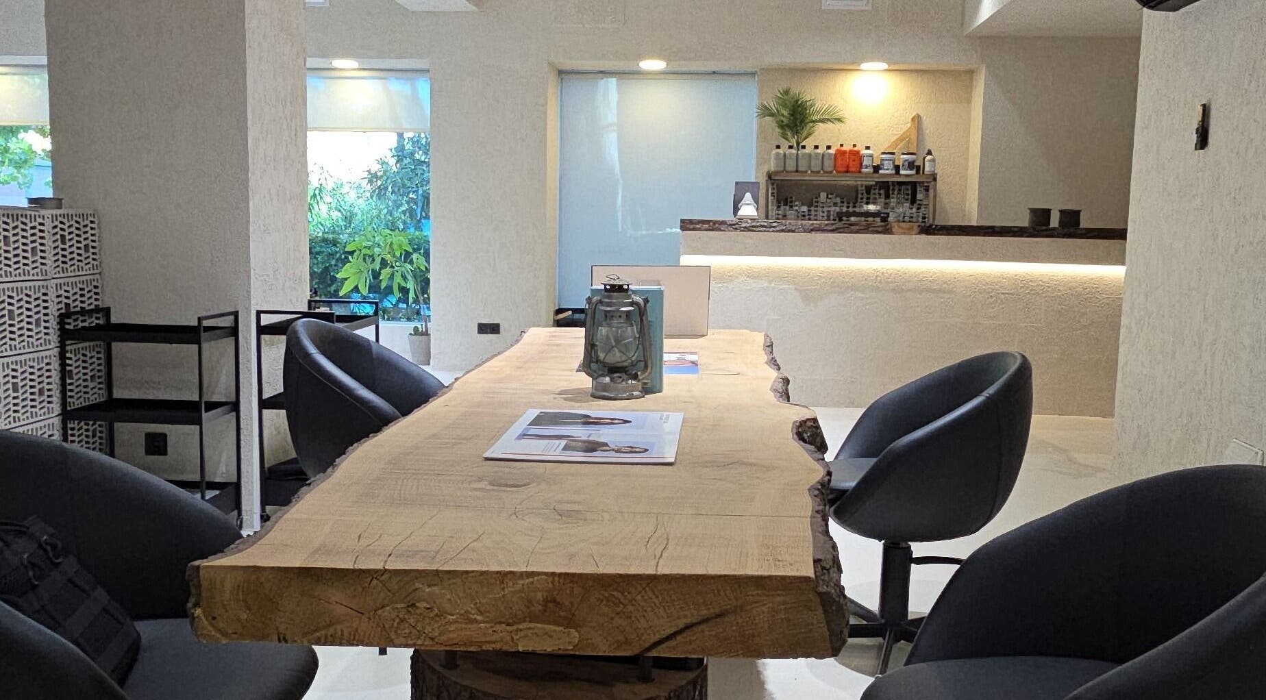 Interior del Akaba Salon en Madrid, con mesa de madera rústica y sillas modernas.