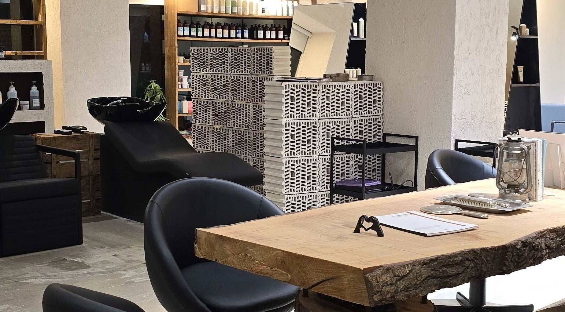 Moderno interior de Akaba Salon en Madrid, Comunidad De Madrid, ES con sillas negras y una mesa rústica.