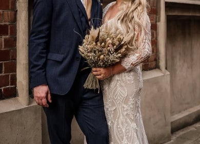 A couple in wedding attire outside Rogue & Vow, Blidworth, England, GB, showcasing intricate dress details.