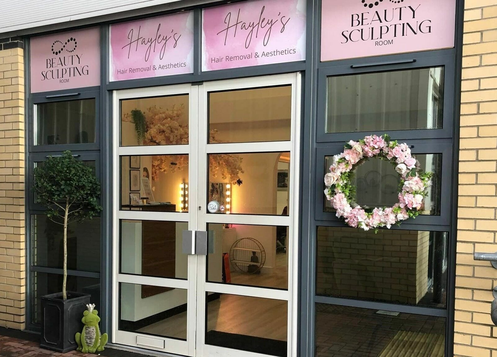 Front entrance of Hayley’s Hair Removal and Aesthetics in Poole, England, GB, featuring a floral wreath and signage.