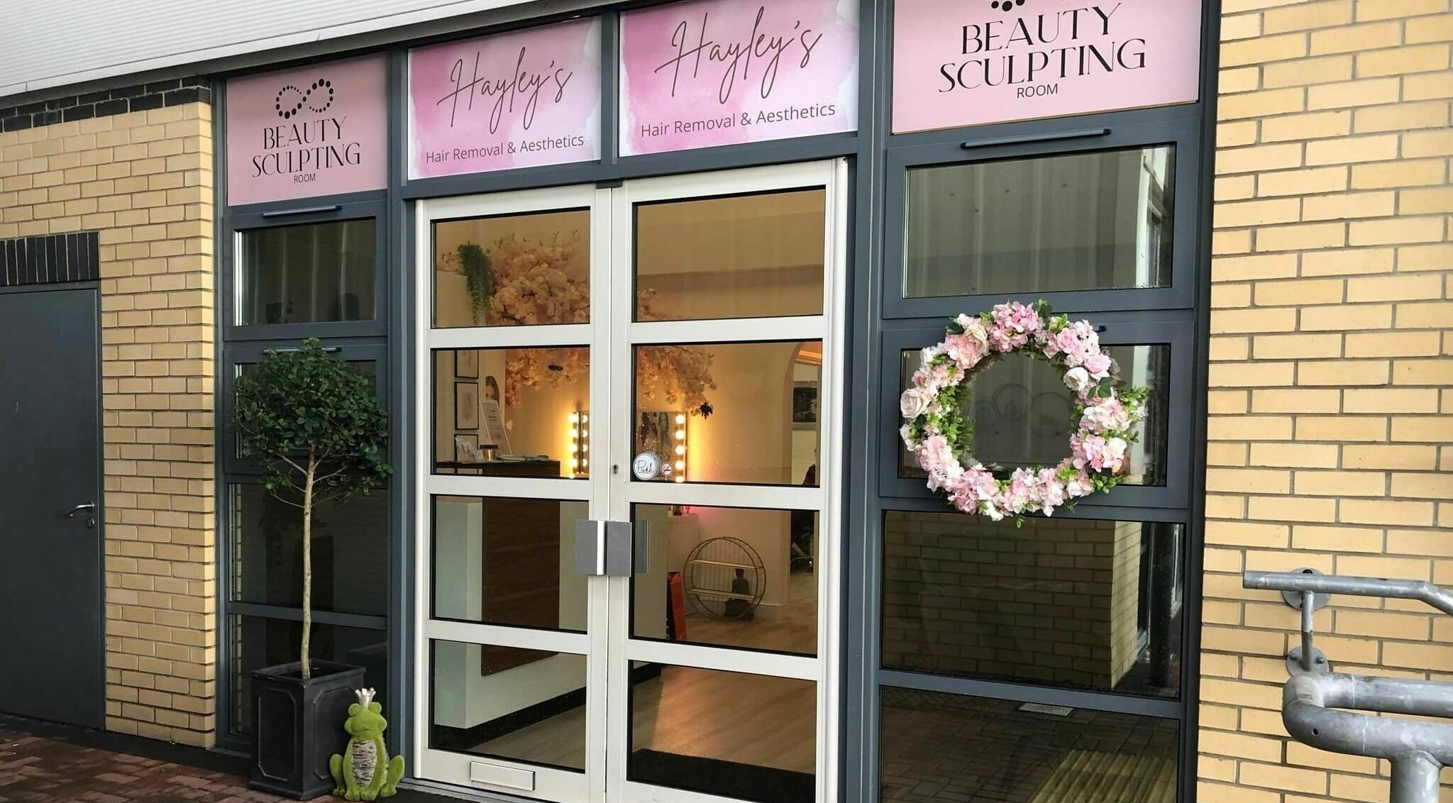 Front entrance of Hayley’s Hair Removal and Aesthetics in Poole, England, GB, featuring a floral wreath and signage.