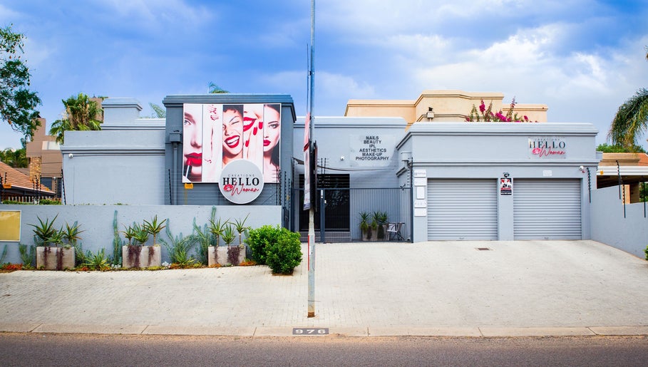 Front view of HelloWoman Faerie Glen, a beauty venue in Pretoria, Gauteng, ZA with vibrant signs and plants.