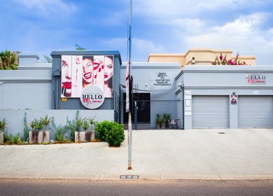 Front view of HelloWoman Faerie Glen, a beauty venue in Pretoria, Gauteng, ZA with vibrant signs and plants.