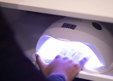 A hand under a UV lamp for nail care at HelloWoman Hazelwood (Menlopark), Pretoria, Gauteng, ZA.