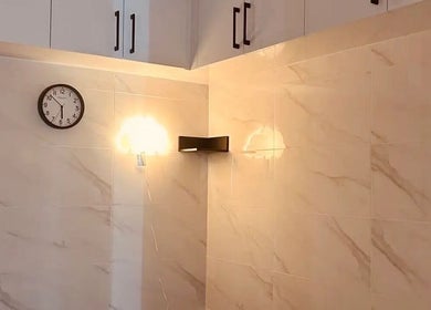 Elegant wall corner at Musi Studio, Richmond, British Columbia, CA with marble tiles and a sleek wall lamp.