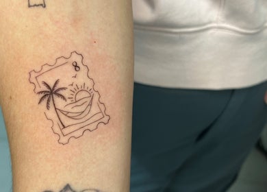 Detailed stamp-style tattoo by Viviana Sp Tattoo Artist in Melbourne, Victoria, AU featuring a sunset and palm tree.