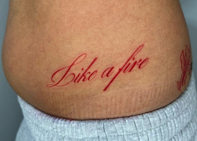 Elegant red script tattoo reading 'Like a fire' by Viviana Sp Tattoo Artist, Melbourne, Victoria, AU.