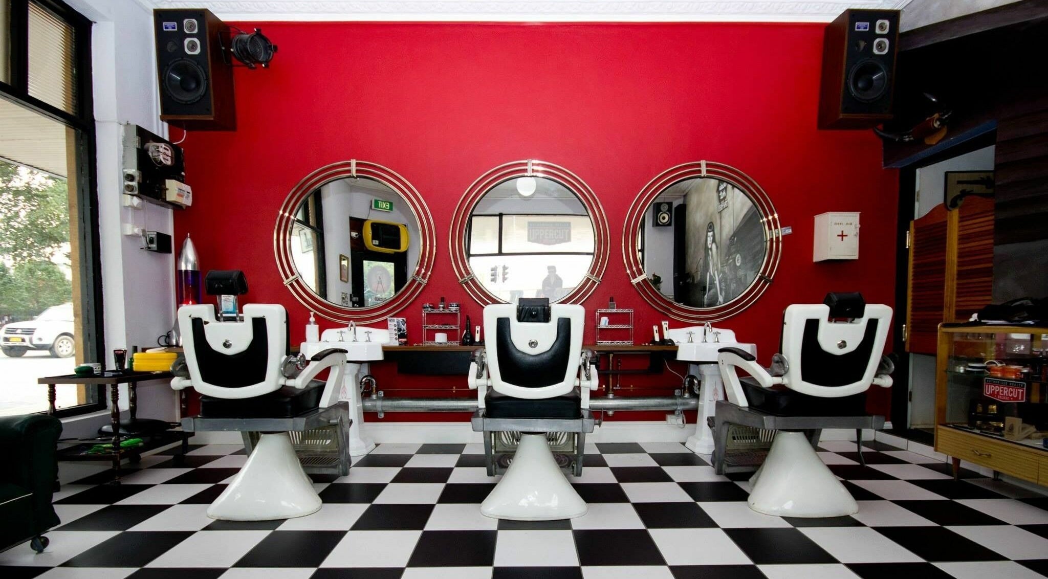 Chic barber chairs and mirrors at Dude Hut, Albury, New South Wales, AU with a stylish red wall.