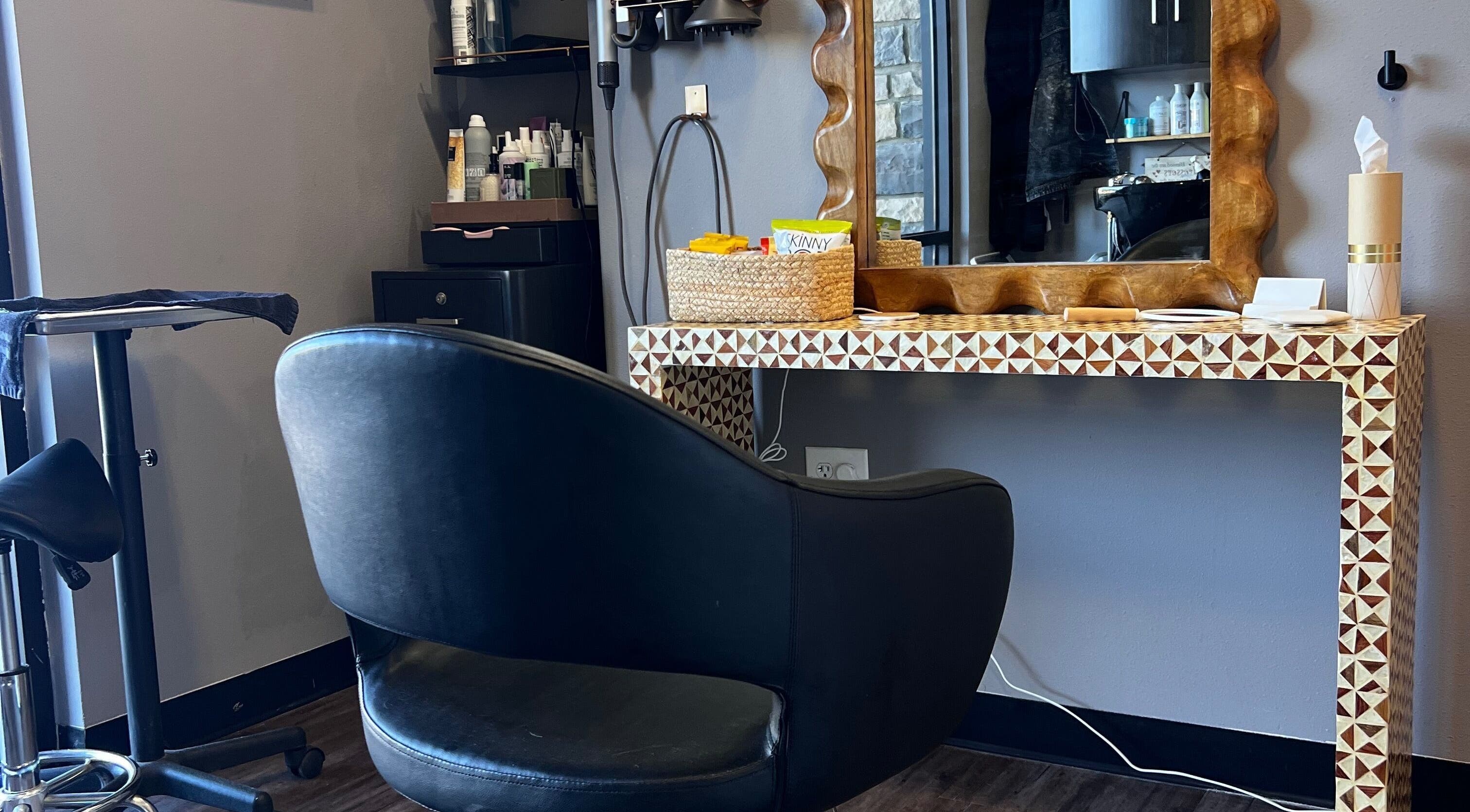 Stylish salon station at Mariah Allison Hair, Flower Mound, Texas, US with elegant black chair and products.