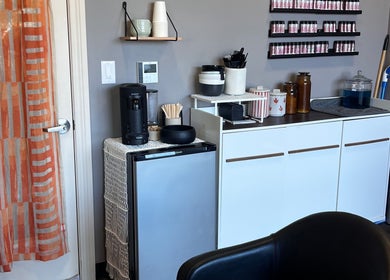 Refreshment station in Mariah Allison Hair, Flower Mound, Texas, US, featuring a coffee maker and shelves.