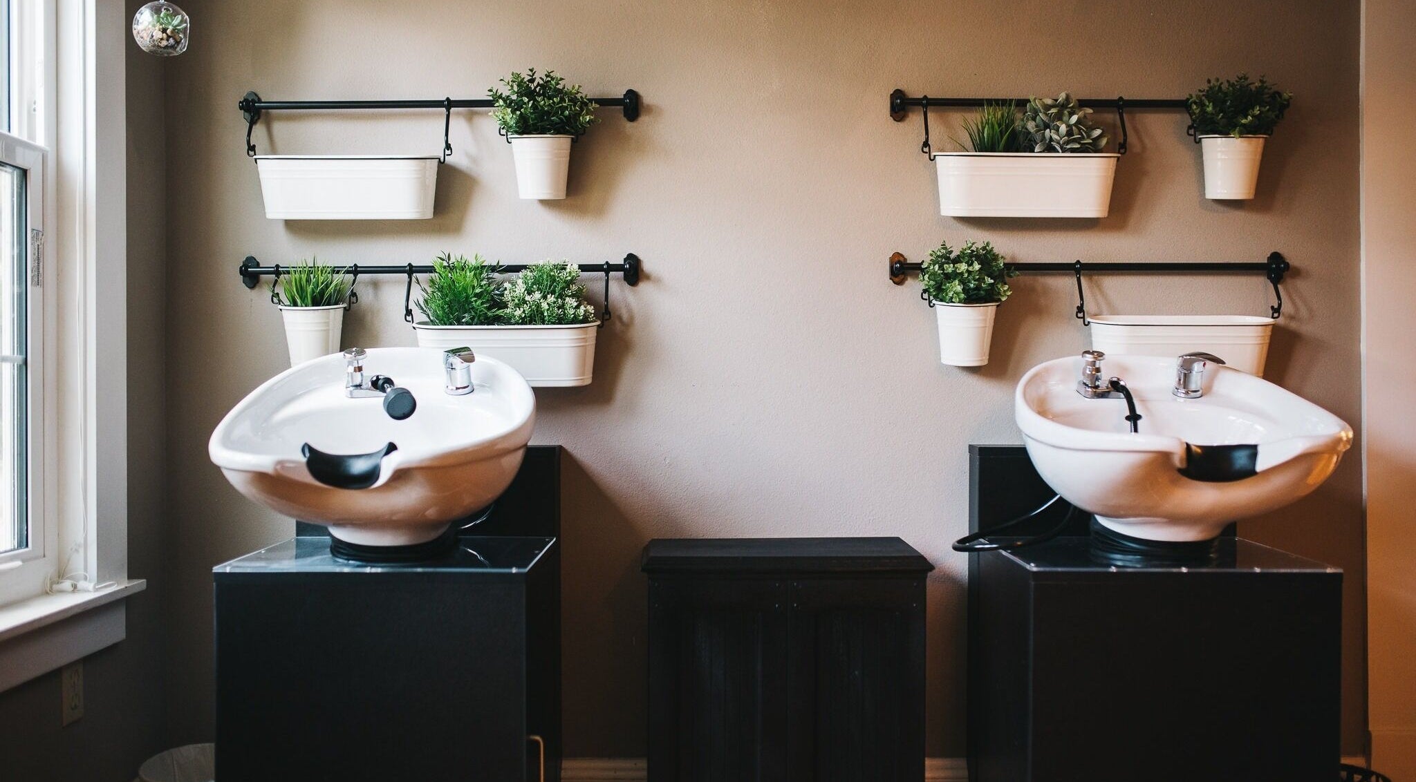 Luxury salon wash stations at The Emerald Fox, Tavares, Florida, US with vibrant plants on walls.