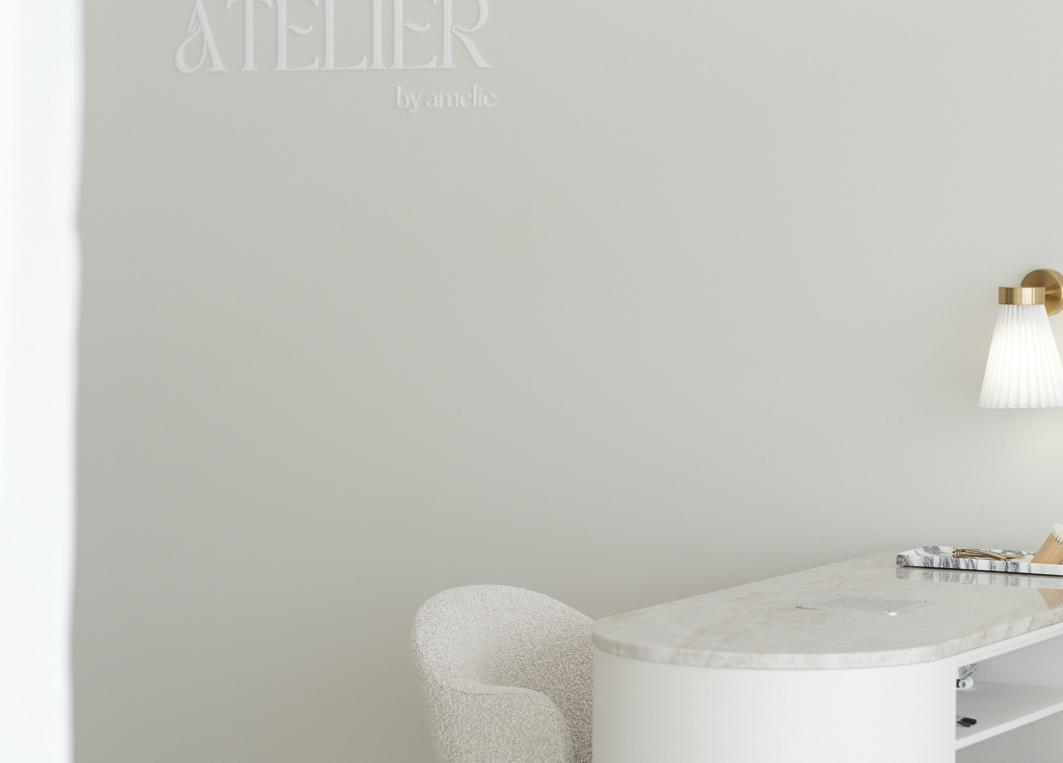 Minimalistic reception desk at The Atelier Double Bay, Double Bay, New South Wales, AU with cozy chair and wall lamp.