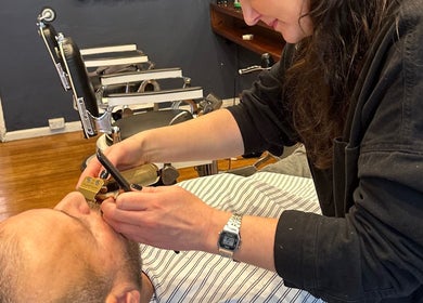 A barber trims a client's beard at Grand Royal Barbers - Darlinghurst in Sydney, New South Wales, AU.