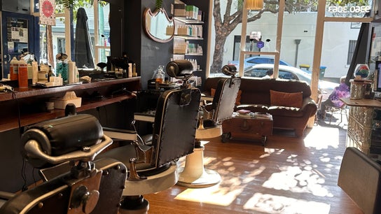 Interior of Grand Royal Barbers - Darlinghurst, Sydney, New South Wales, AU, showcasing vintage chairs and cozy seating.