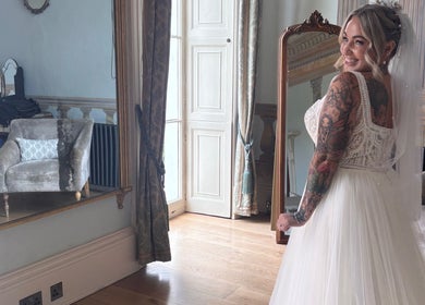 Bride smiling in mirror at Trim N Tonic, Teignmouth, England, GB. Elegant room decor enhances bridal beauty.