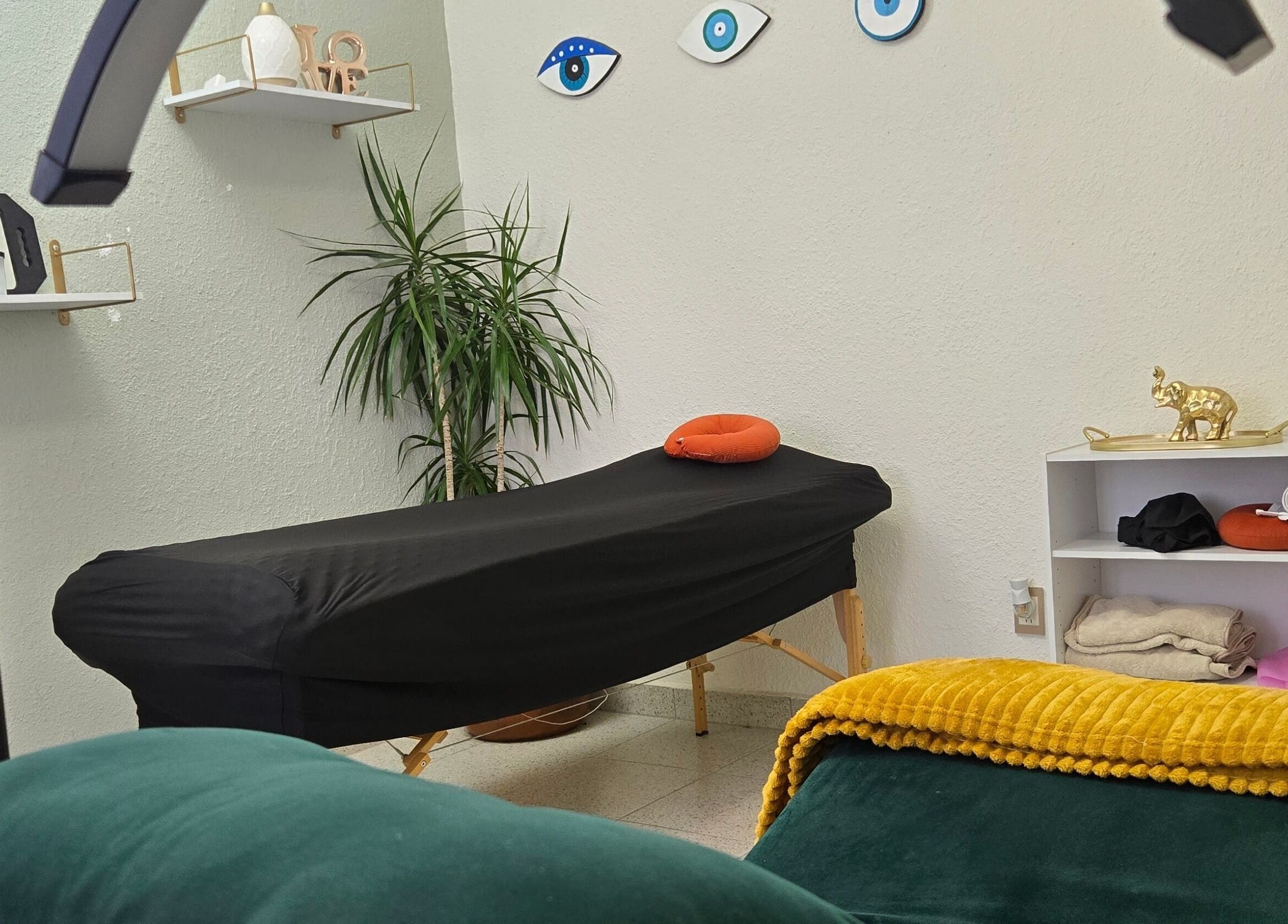 Sala de tratamientos de Pastiche Studio en Chihuahua, Chihuahua, MX con camilla negra y decoración acogedora.