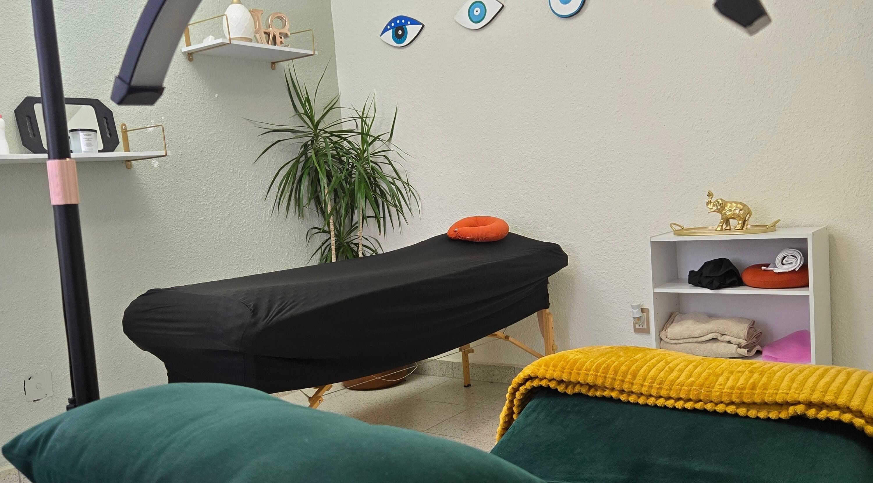 Sala de tratamientos de Pastiche Studio en Chihuahua, Chihuahua, MX con camilla negra y decoración acogedora.