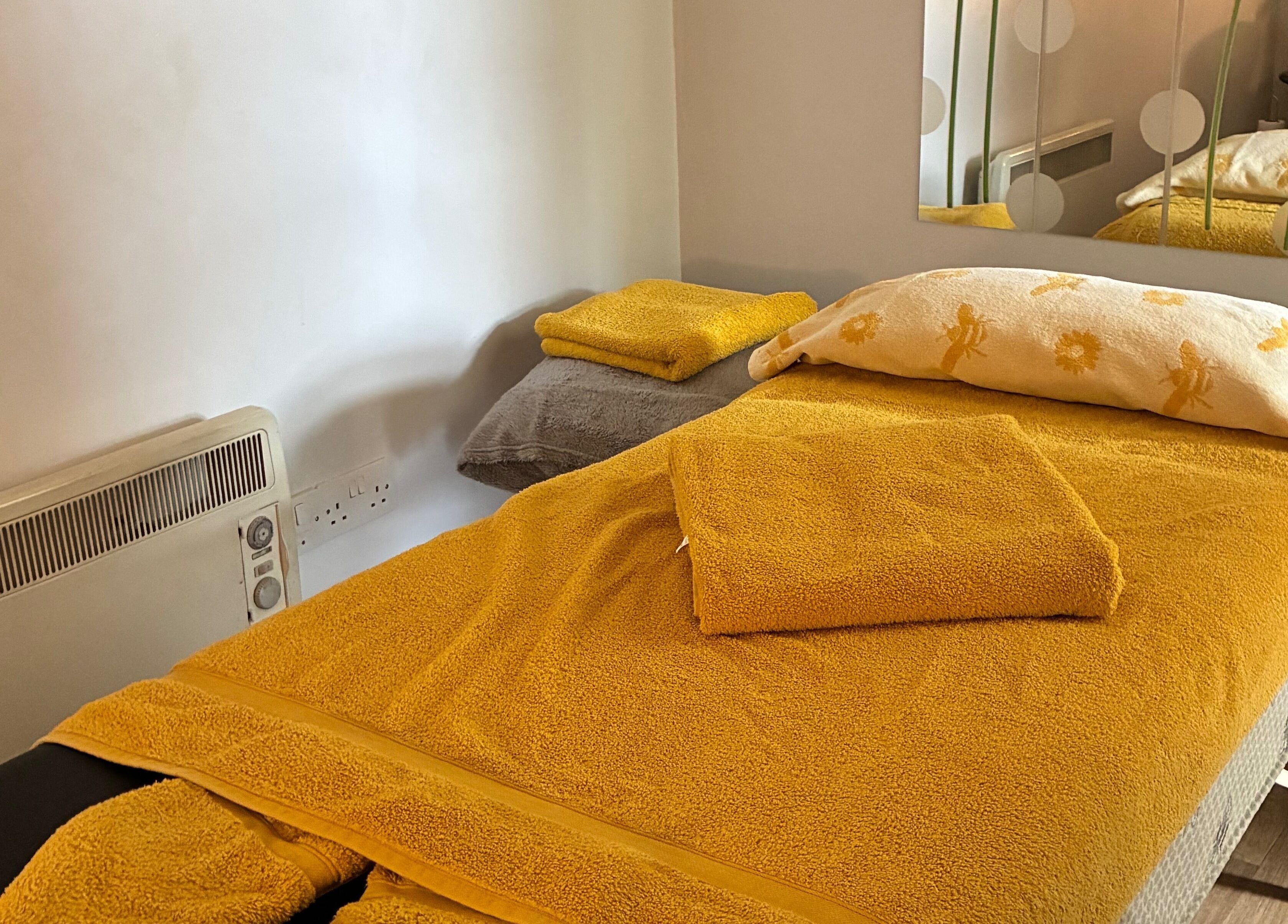 Massage table in Tranquil Fields at Farrington Gurney, England, GB, with yellow towels for a serene ambiance.