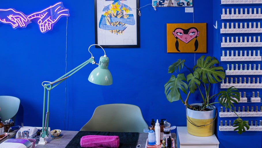 Tru Nail Art's vibrant workspace with blue walls in Brighton, England, GB. Features art, plants, and nail polishes.