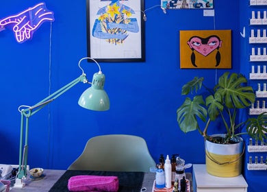 Tru Nail Art's vibrant workspace with blue walls in Brighton, England, GB. Features art, plants, and nail polishes.