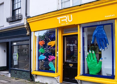 Colorful storefront of Tru Nail Art in Brighton, England, GB showcasing vibrant hand art displays.