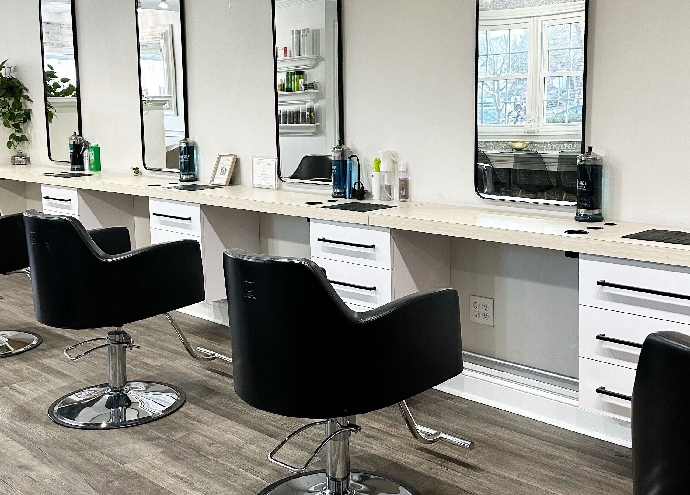 Modern styling stations at Bounce Hair Salon in Port Jefferson, New York, US with sleek black chairs.