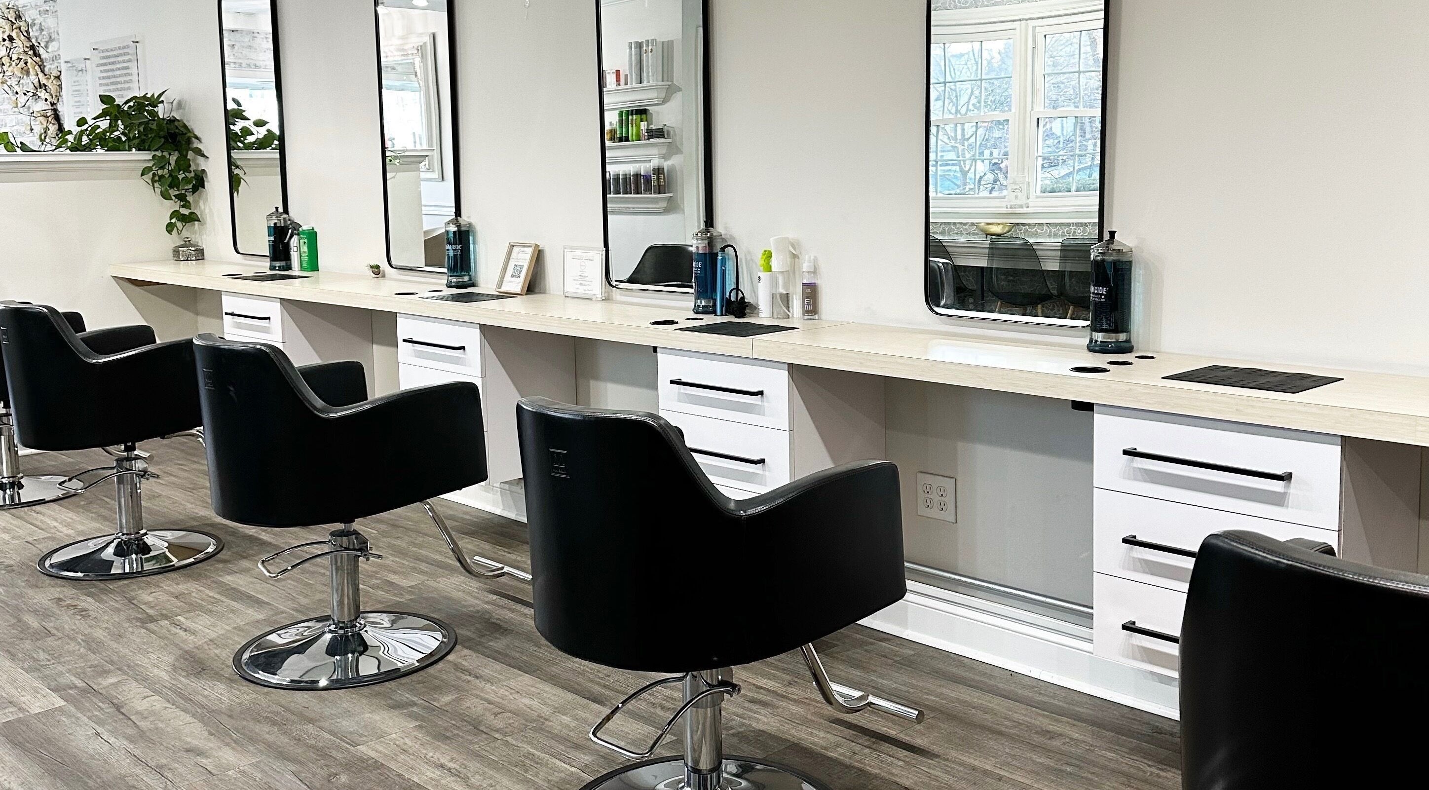 Modern styling stations at Bounce Hair Salon in Port Jefferson, New York, US with sleek black chairs.
