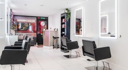 Modern salon seating area at Elliott Dean, Romford, England, GB, with stylish black chairs and illuminated mirrors.