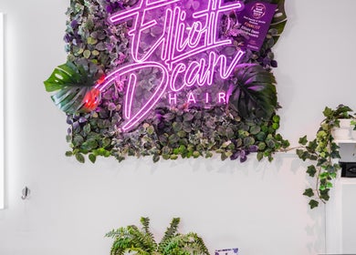Neon sign of Elliott Dean surrounded by lush greenery at the Romford, England, GB location.