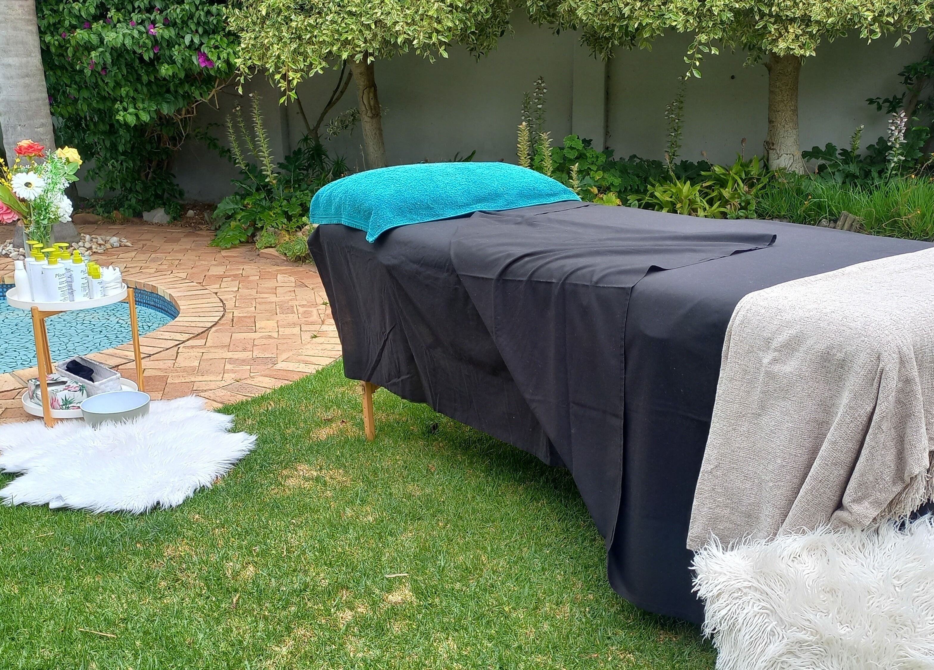 Outdoor massage setup at Mello's Mobile Beauty Spa, Gqeberha, Eastern Cape, ZA, near a tranquil pool.