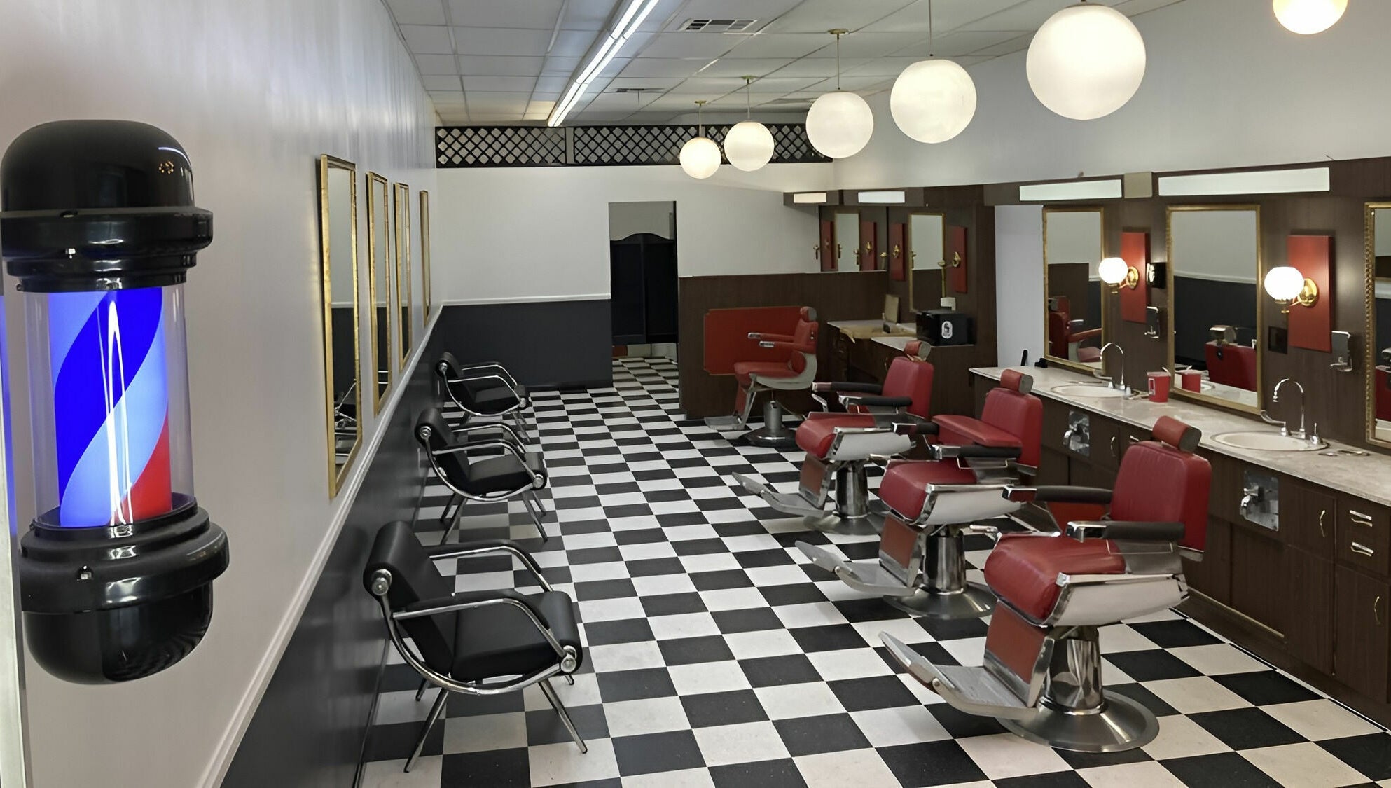 Interior of The Checkmate Barbershop with red chairs and mirrors in Montebello, California, US.