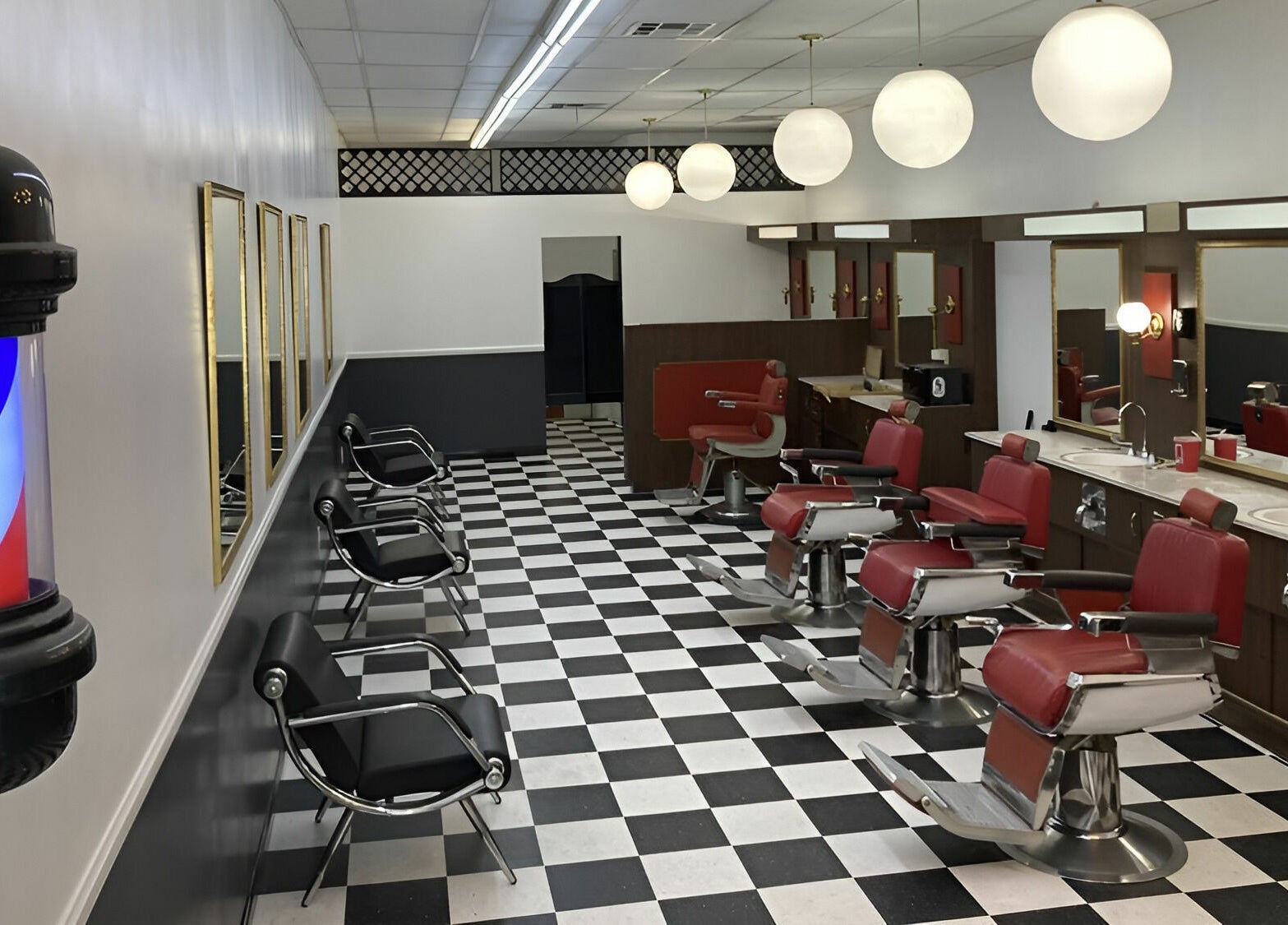 Interior of The Checkmate Barbershop with red chairs and mirrors in Montebello, California, US.