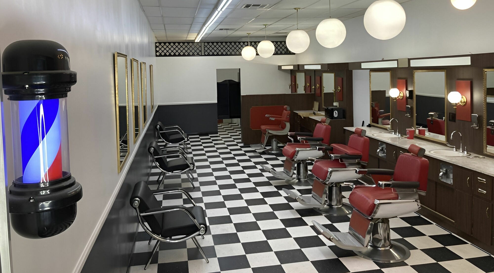 Interior of The Checkmate Barbershop with red chairs and mirrors in Montebello, California, US.