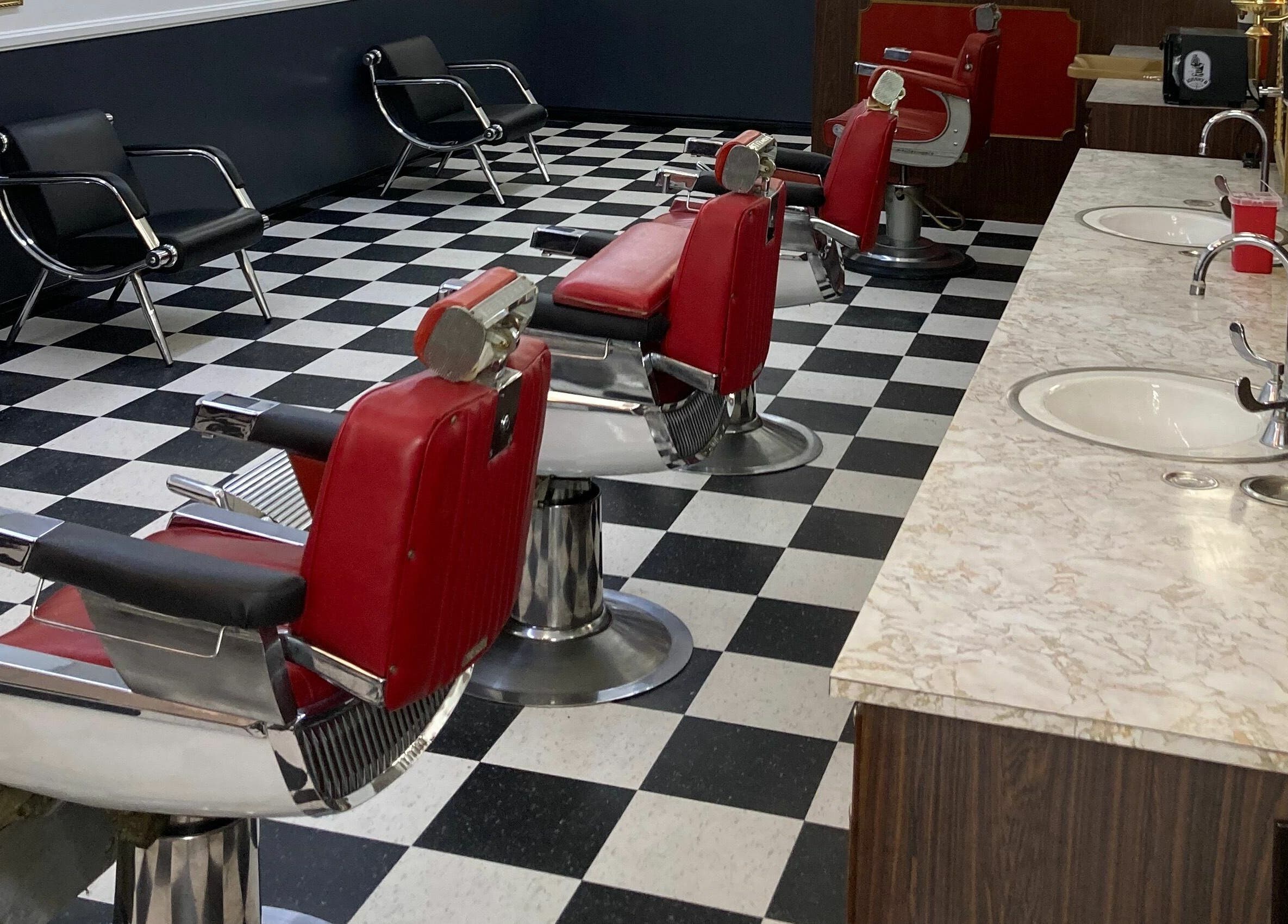 The Checkmate Barbershop in Montebello, California, US with red barber chairs and a retro checkered floor.