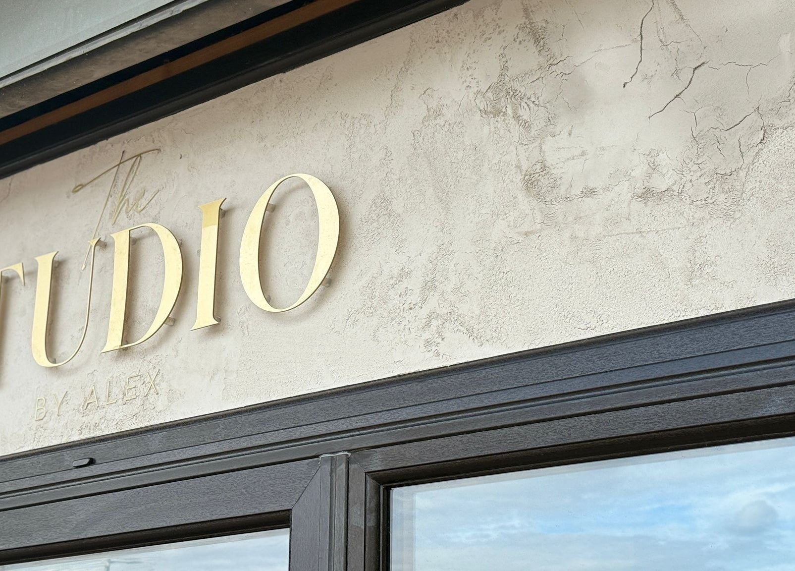 Front entrance sign of The Studio By Alex in Billingham, England, GB, featuring elegant gold lettering.