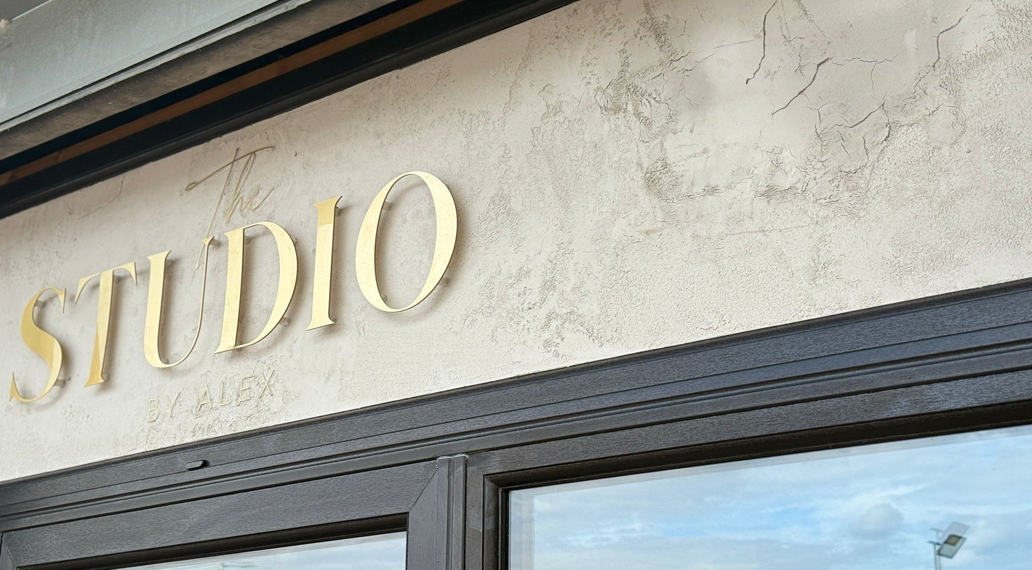Front entrance sign of The Studio By Alex in Billingham, England, GB, featuring elegant gold lettering.