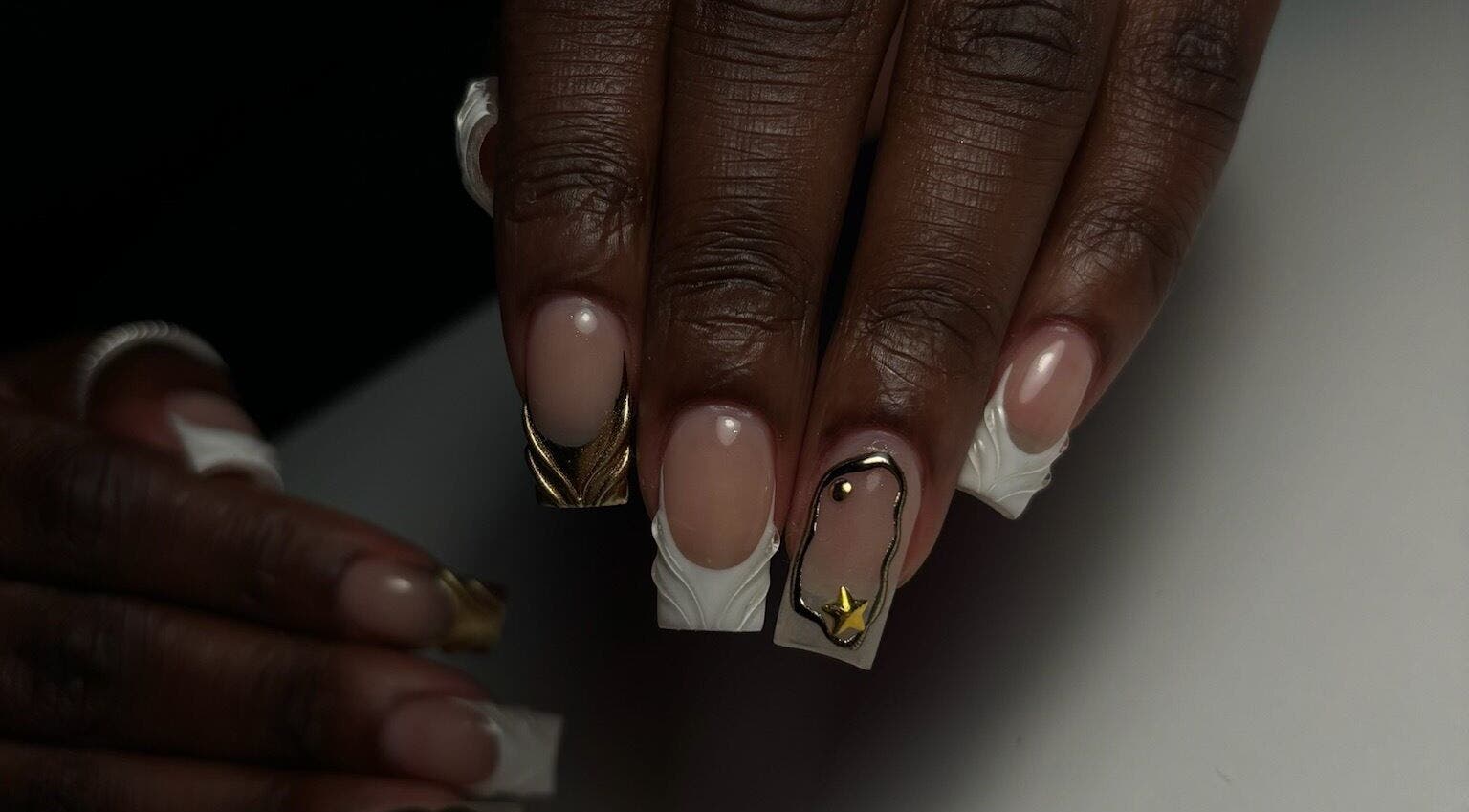 Manucure artistique à JD Beauty Studio, Laval, Québec, CA, avec motifs dorés et blancs.