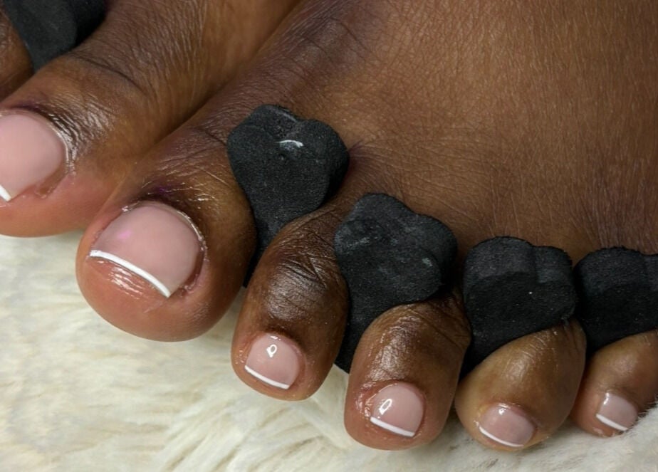 Pédicure professionnelle chez JD Beauty Studio, Laval, Québec, CA avec écarteurs noirs et vernis élégant.