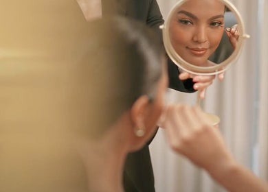 A woman applies makeup in a mirror at NEW Lounge Boracay, Aklan, PH, showcasing beauty services.
