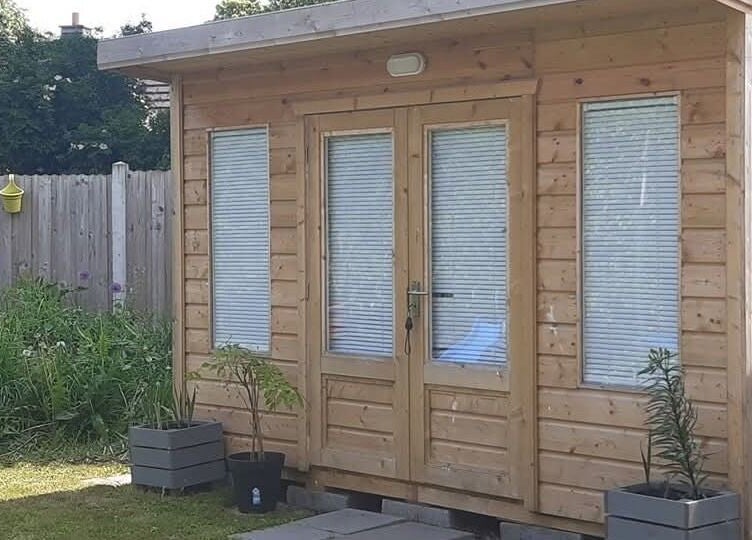 Wooden cabin at The Beauty Garden in Bray, County Wicklow, IE, surrounded by greenery.