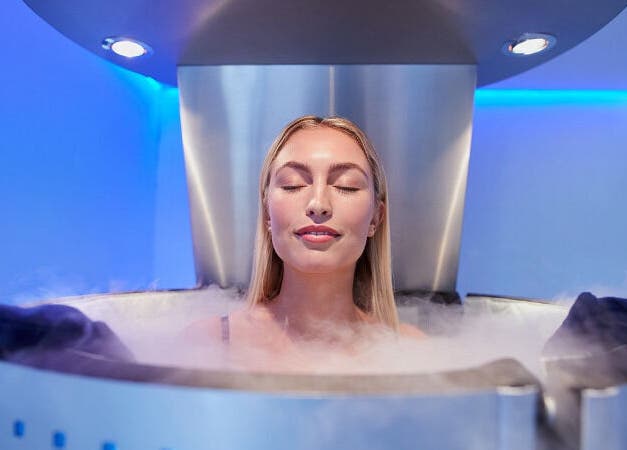 Frau in Kryokammer bei Cryo Health Küsnacht ZH, Erlenbach, Zürich, CH, genießt beruhigendes Kälteerlebnis.