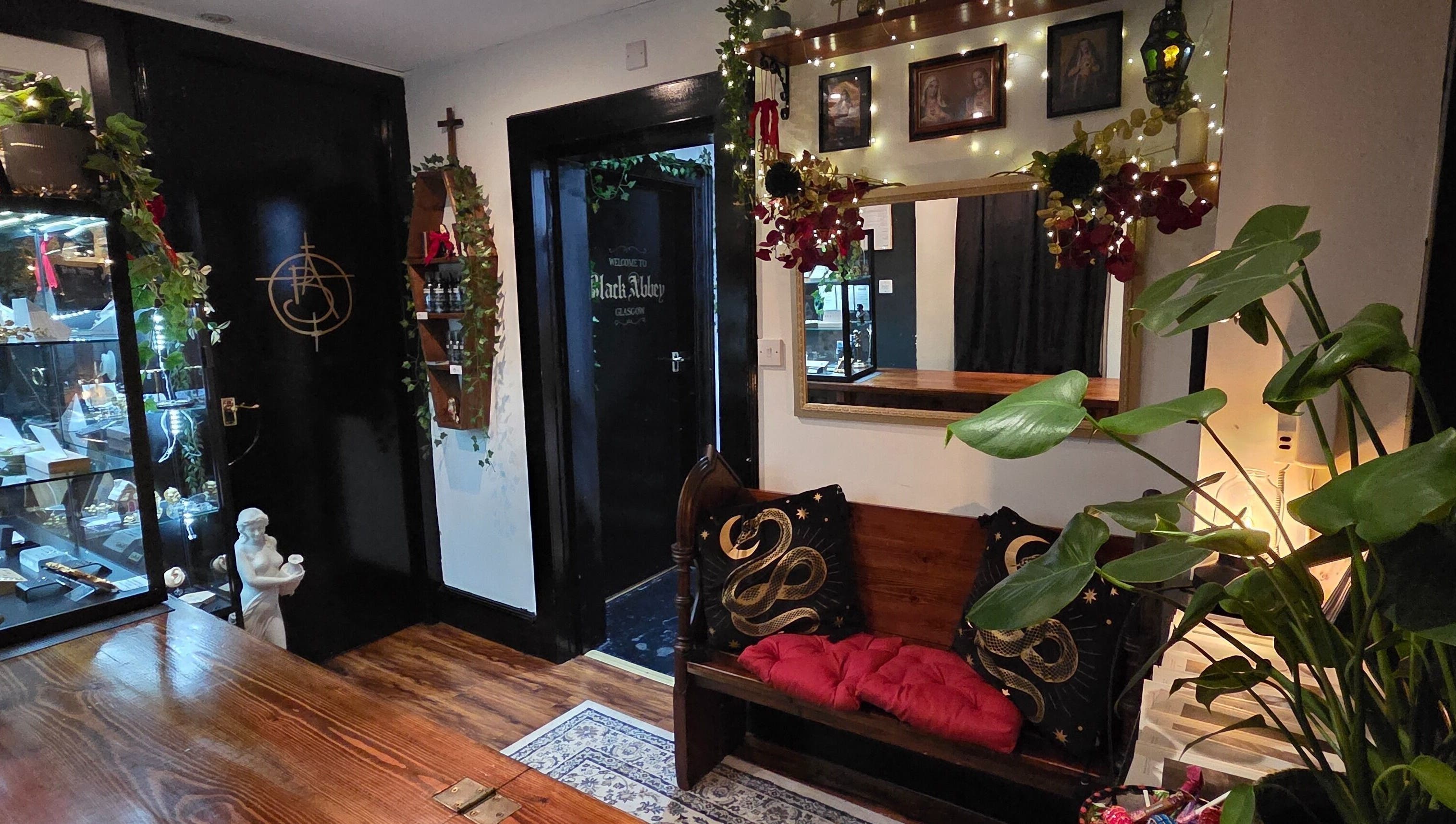 Elegant seating at Black Abbey Tattoo and Piercing, Glasgow, Scotland, GB, showcasing ornate decor and plant accents.