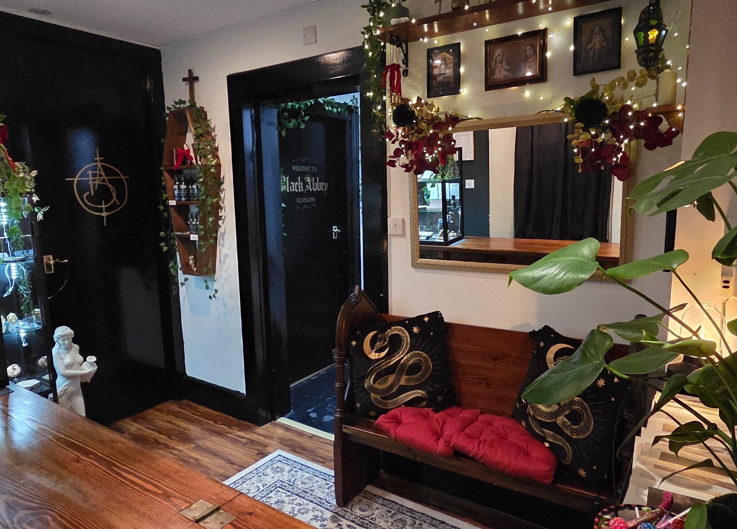 Elegant seating at Black Abbey Tattoo and Piercing, Glasgow, Scotland, GB, showcasing ornate decor and plant accents.
