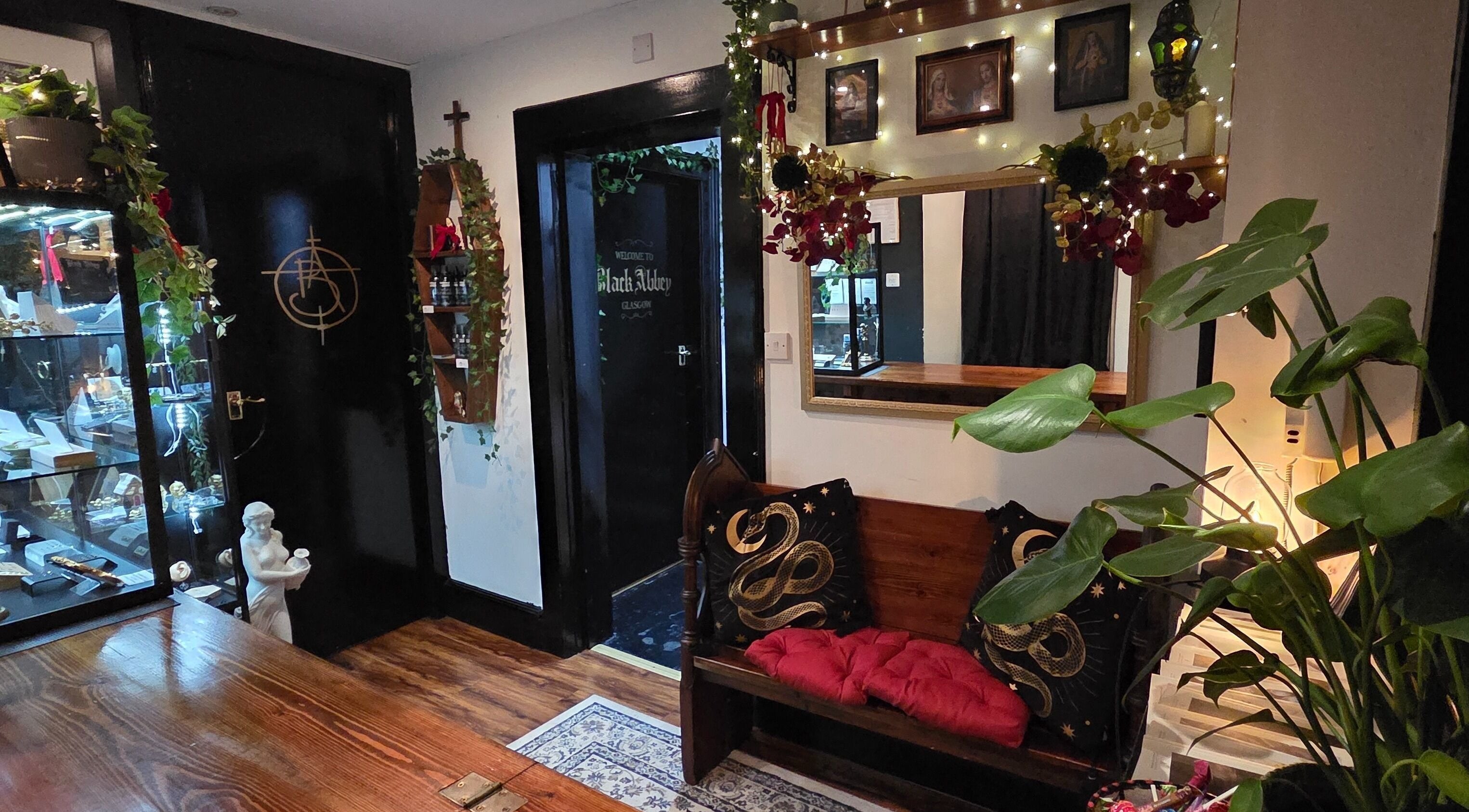 Elegant seating at Black Abbey Tattoo and Piercing, Glasgow, Scotland, GB, showcasing ornate decor and plant accents.