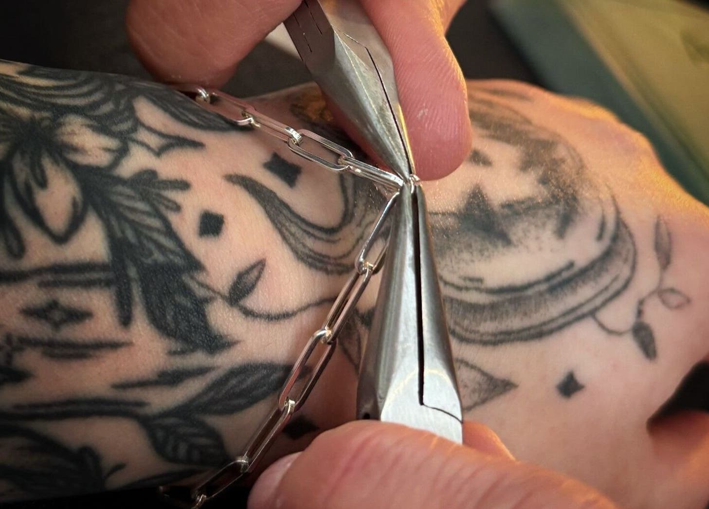 Detail of a tattooed arm with jewelry in Black Abbey Tattoo and Piercing, Glasgow, Scotland, GB.
