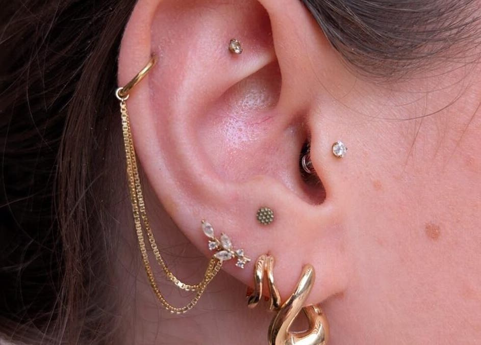 Close-up of ear piercings at Black Abbey Tattoo and Piercing, Glasgow, Scotland, GB with gold earrings.