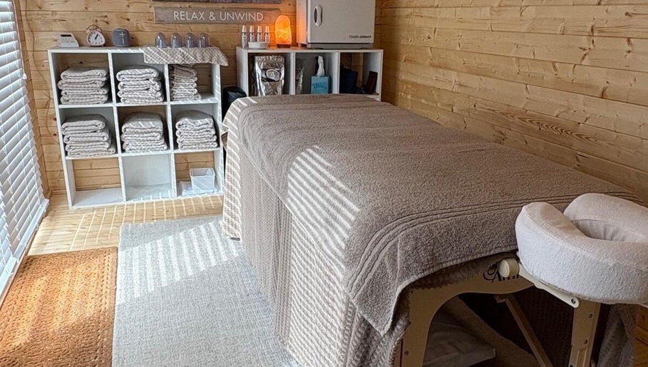 Serene massage room at Rio Bluebell Therapies, Salisbury, England, GB with soft linens and wooden decor.