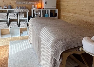 Serene massage room at Rio Bluebell Therapies, Salisbury, England, GB with soft linens and wooden decor.