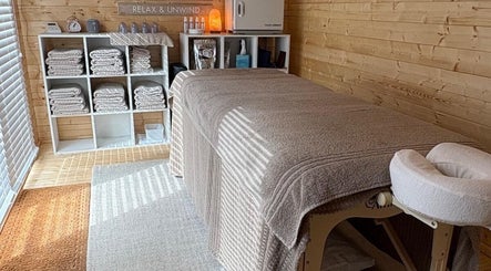 Serene massage room at Rio Bluebell Therapies, Salisbury, England, GB with soft linens and wooden decor.